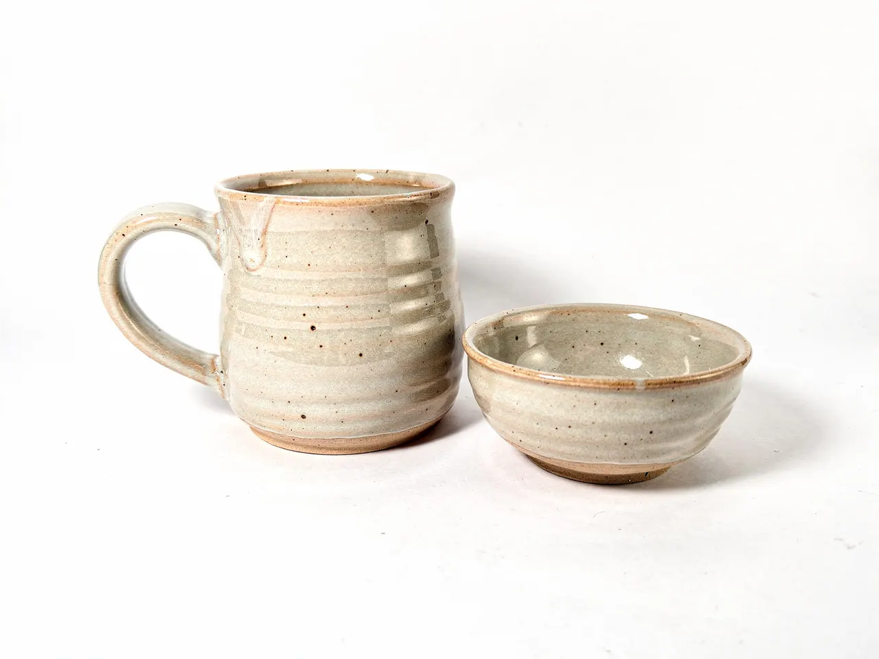 Taza y cuenco de cerámica artesanal sobre fondo blanco
